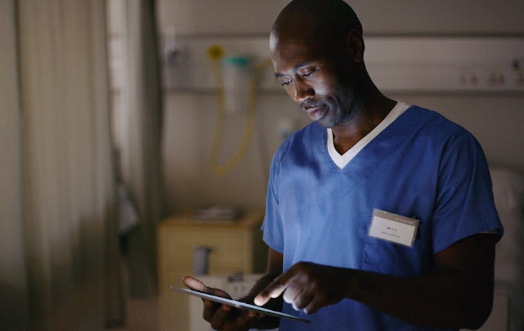 doctor in scrubs using tablet