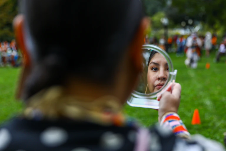 A woman checks her hair in the mirror.