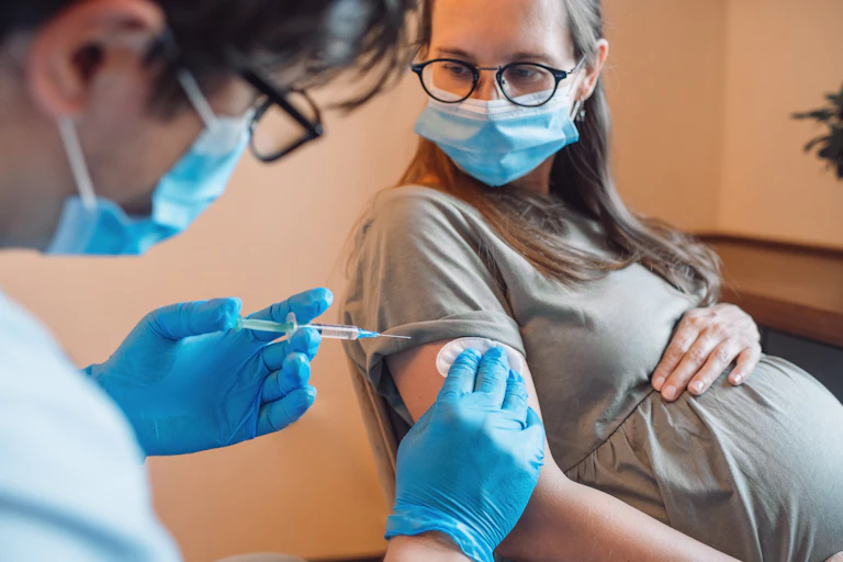 Pregnant woman getting vaccine at home.