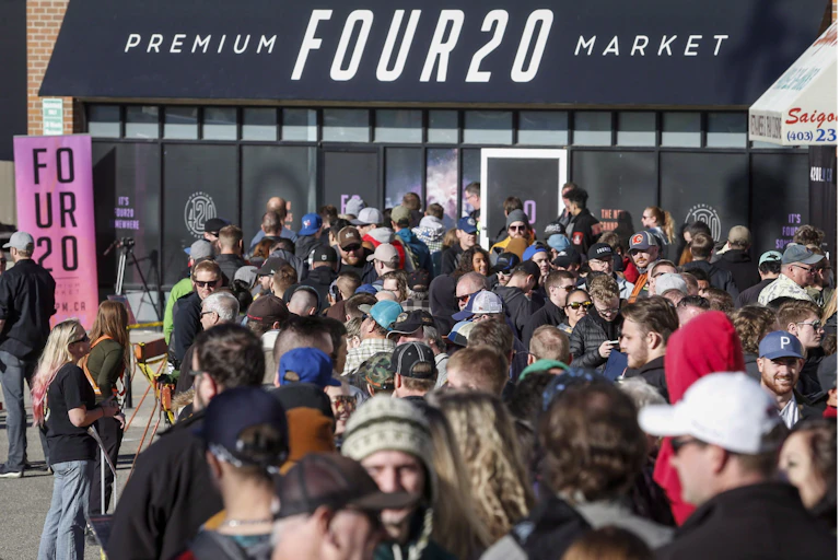 A crowd of people are seen outside a store called premium four20 market.