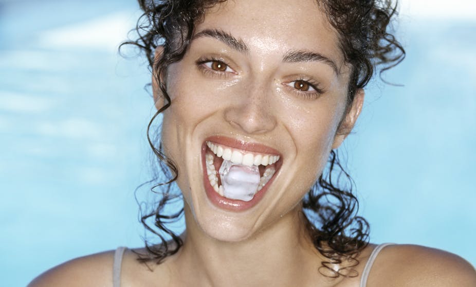 Woman holds an ice cube between her teeth