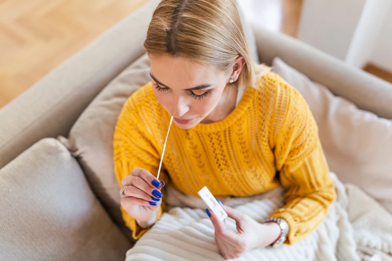 Young woman at home swabbing herself for COVID