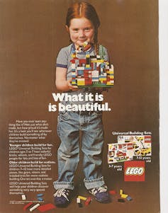 Young girl in overalls, holding lego blocks.
