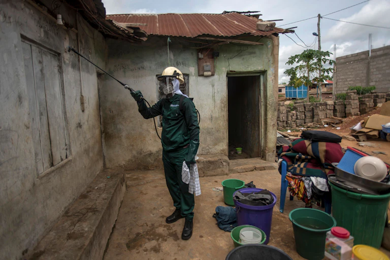 man wearing hazmat suit spraying houses