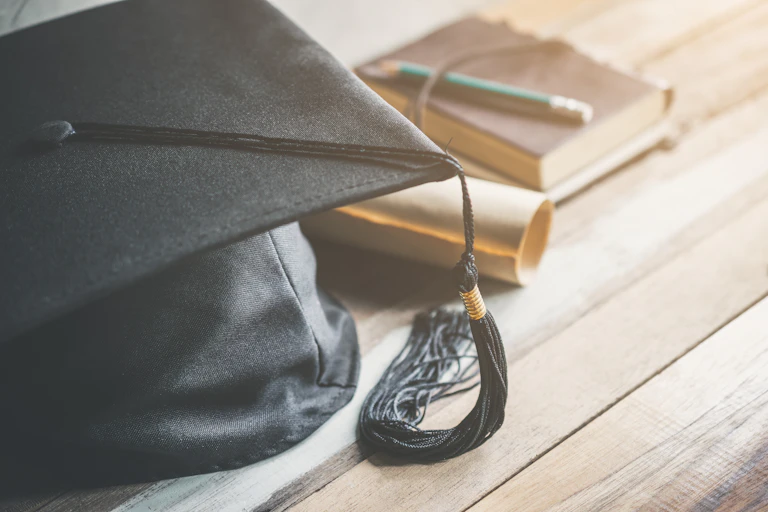 graduation cap, hat with degree paper on wood table graduation concept.