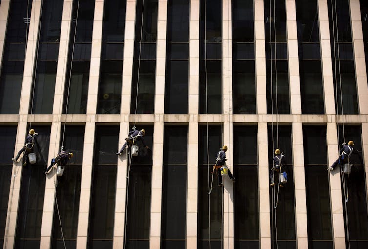 A team of window washers descend on ropes as they clean an office building
