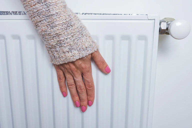 Woman touching radiator.