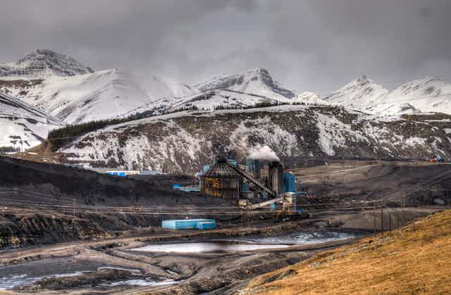Coal mine surrounded by snow-capped mountains