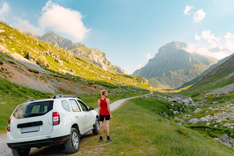 Woman standing beside her SUV looking at the mountains