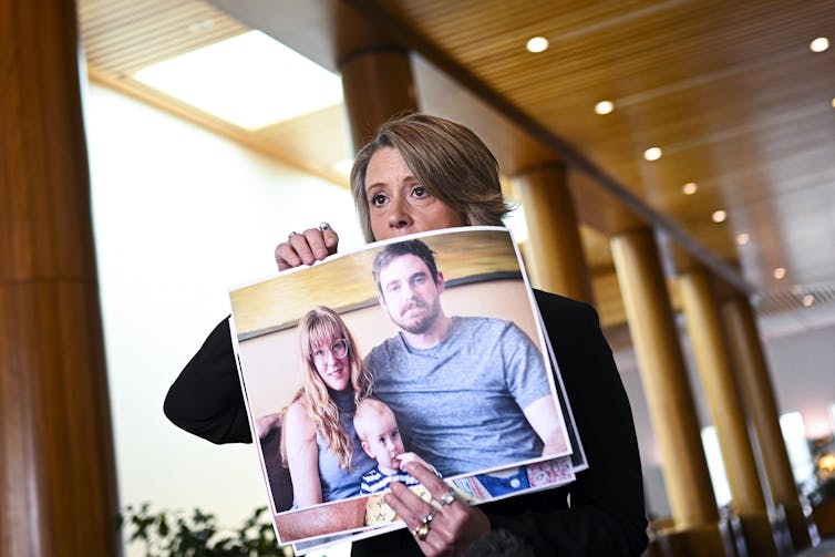 Labor senator Kristina Keneally holds up photos of Australians stranded.
