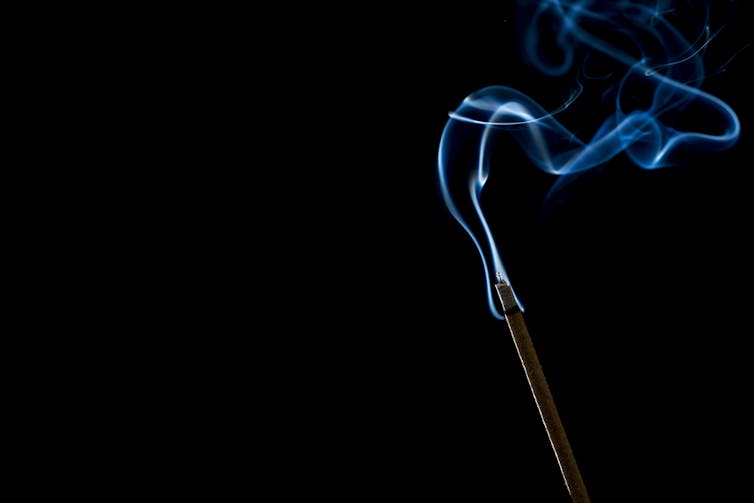 Lit incense stick with smoke wafting