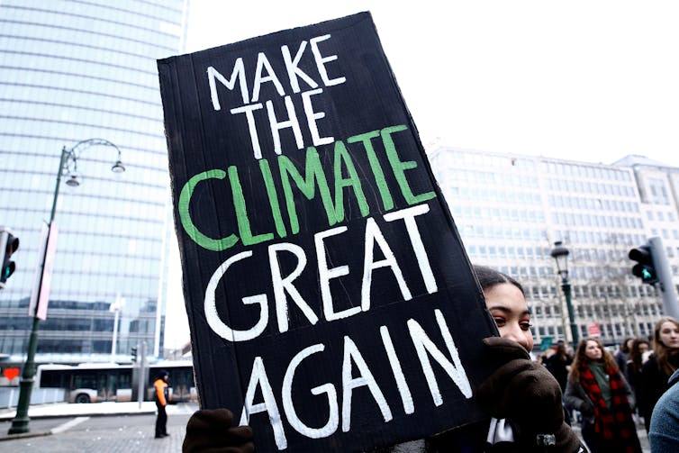 Woman holds sign reading 'Make the Climate Great Again'