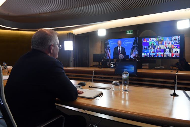 Man at desk looks at two TV screens