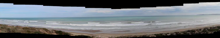 Panorama of a beach with lots of waves.