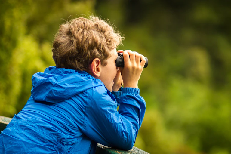 young boy looking through binoculars