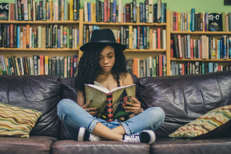 Woman reading a book on a sofa.