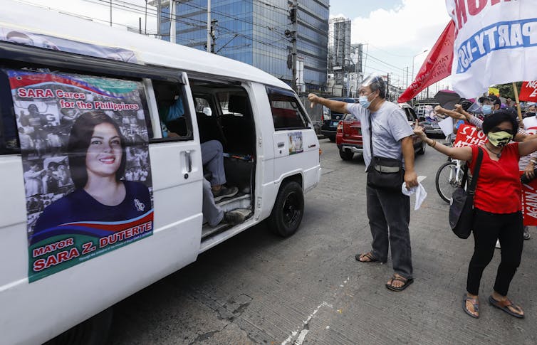 Protesters shake their fist at a minibus with a picture of Sara Duterte, who is thought to be preparing a bid for the Philippines presidency.