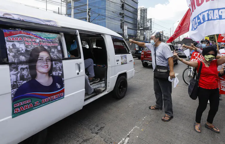 Protesters shake their fist at a minibus with a picture of Sara Duterte, who is thought to be preparing a bid for the Philippines presidency.