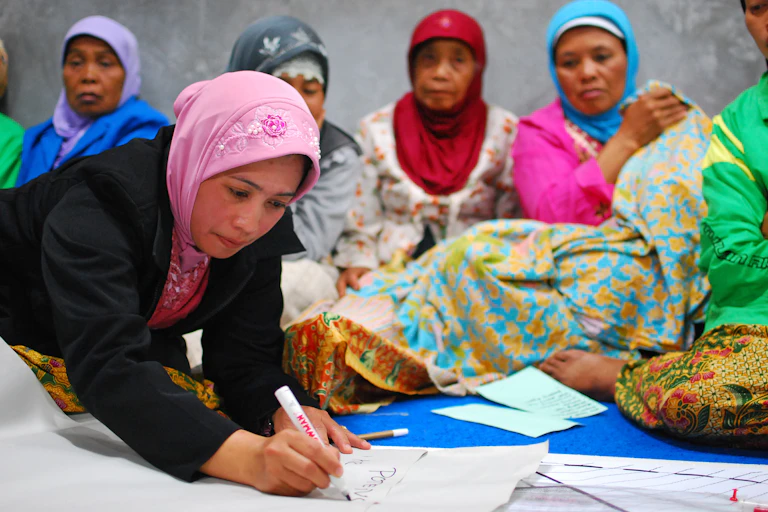 Women sit and write on paper