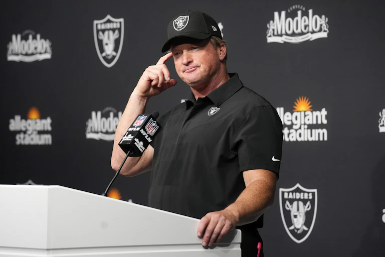 A man stands behind a podium scratching his head