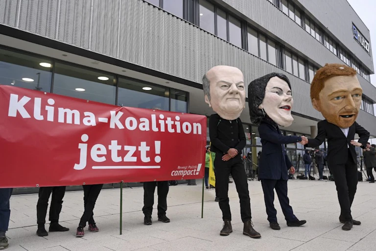 Personnes portant des masques des trois principaux dirigeants de la future coalition allemande