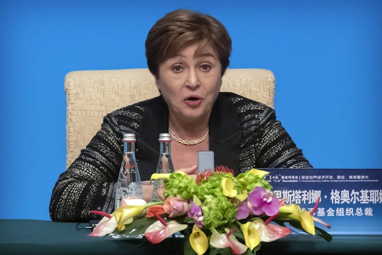 Kristalina Georgieva sits at a table adorned with a floral bouquet during a speech