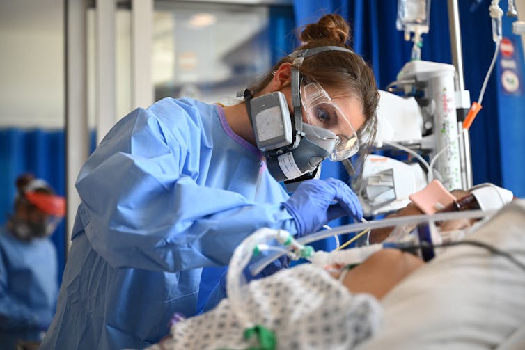 A nurse treats a patient in a British COVID hospital ward