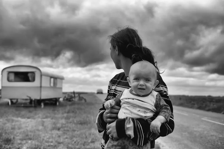 Woman with baby looking back at a caravan