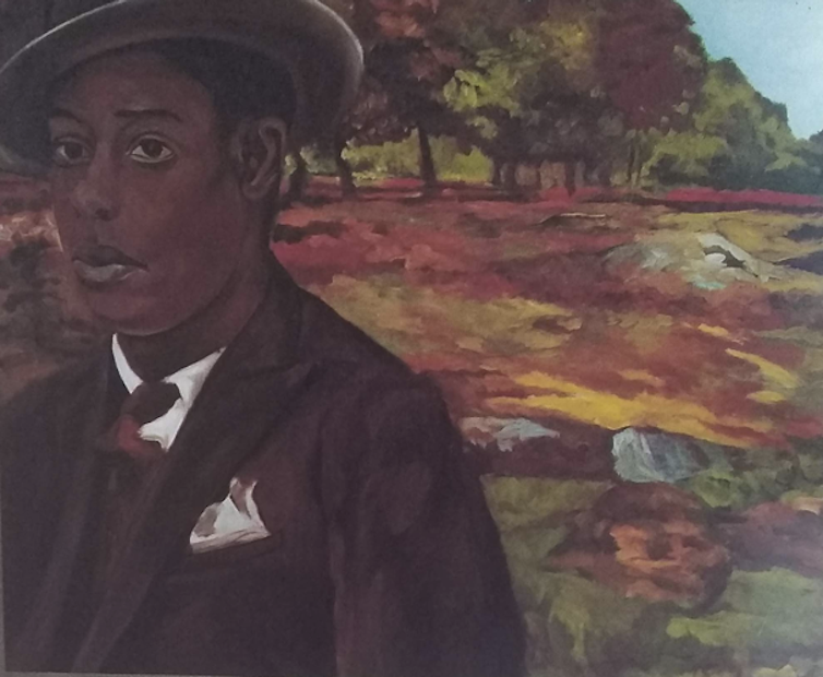 Man in suit and hat stands in the countryside.