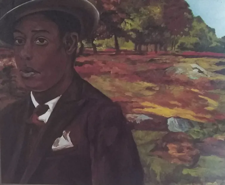 Man in suit and hat stands in the countryside.