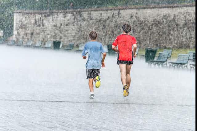 Deux jeunes hommes courent sous une pluie battante