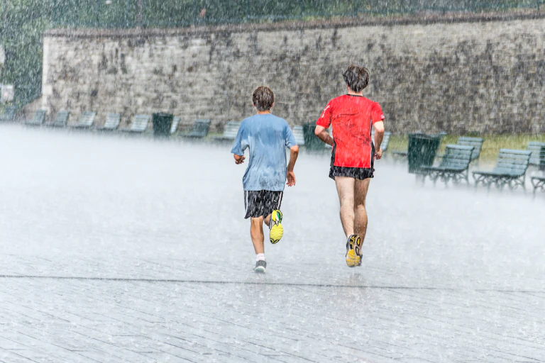 Deux jeunes hommes courent sous une pluie battante