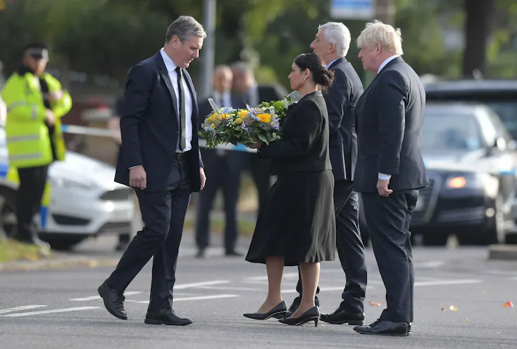 Keir Starmer, Priti Patel, Lynsey Hoyle and Boris Johnson dressed in black at the site of David Amess's murder. Patel is holding a wreath of flowers.