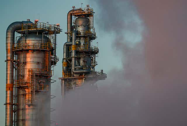 Silver petrochemical plant slightly obscured by a pink cloud