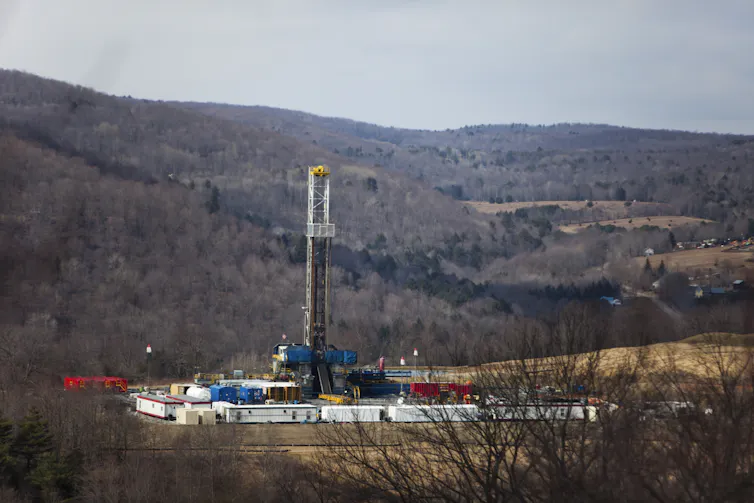 Tall drilling machinery against a natural landscape.