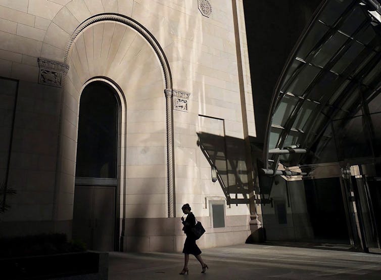 A woman is seen in silhouette walking in Toronto's financial district.