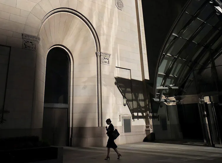 A woman is seen in silhouette walking in Toronto's financial district.