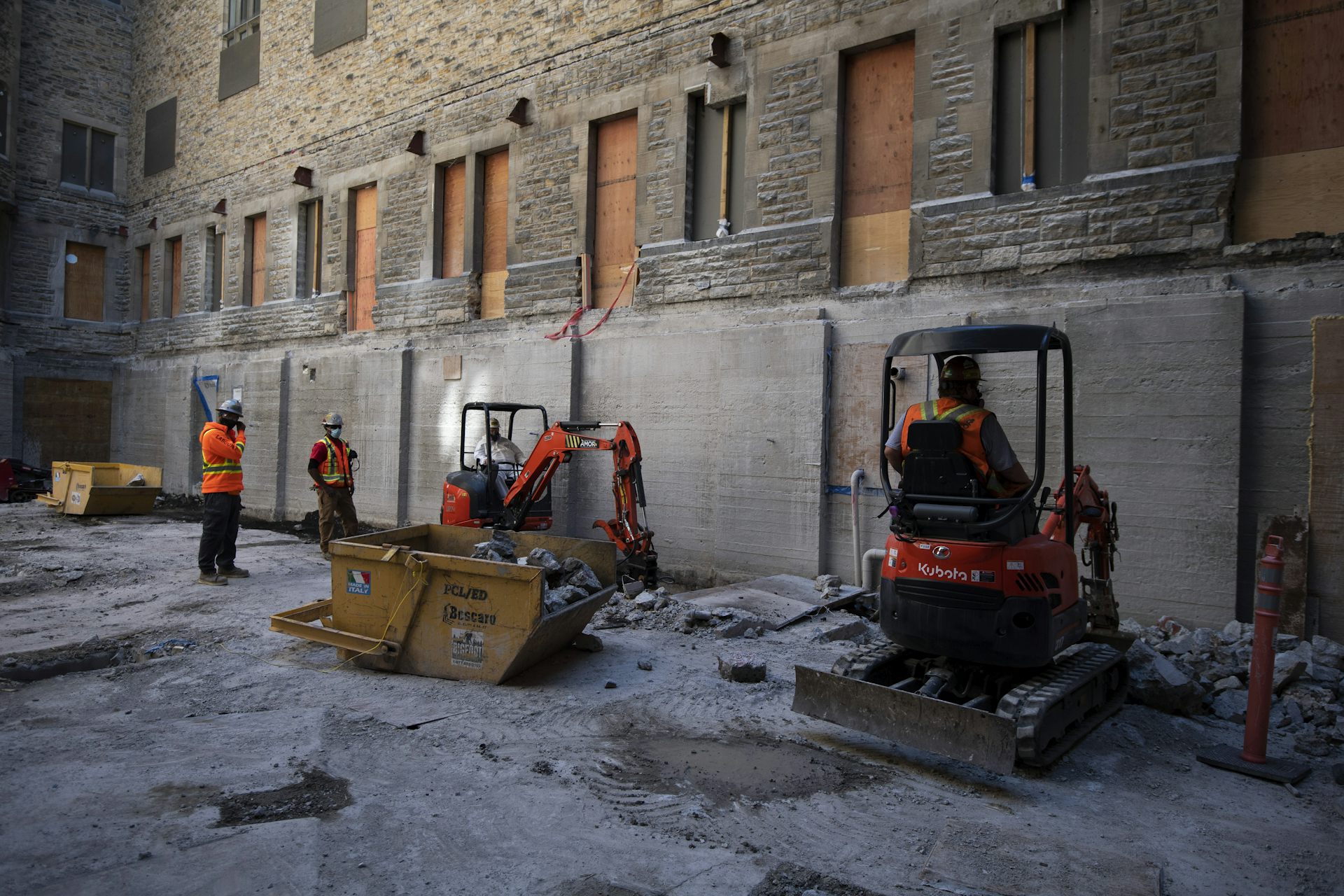 Construction workers in orange safety vests do work on Parliament Hill