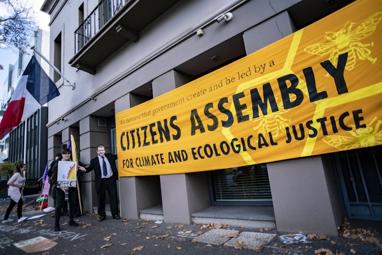 A banner reading 'We demand that government create and be led by a Citizens Assembly for climate and ecological justice'