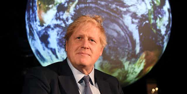 Prime Minister Boris Johnson standing in front of an image of the Earth