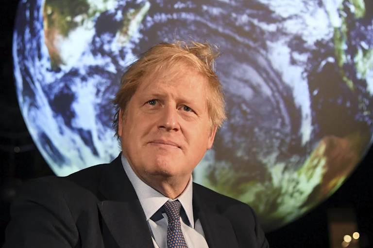 Prime Minister Boris Johnson standing in front of an image of the Earth