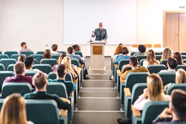 A college professor lectures to a room of students.
