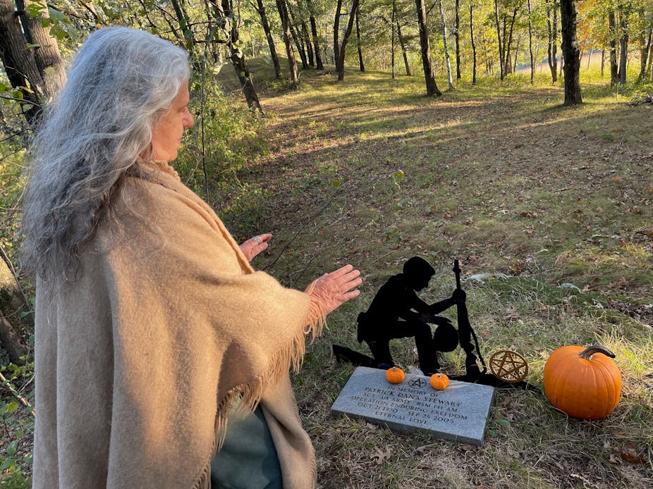 Wiccan high priestess performs ceremony in front of military grave inscribed with a pentagram