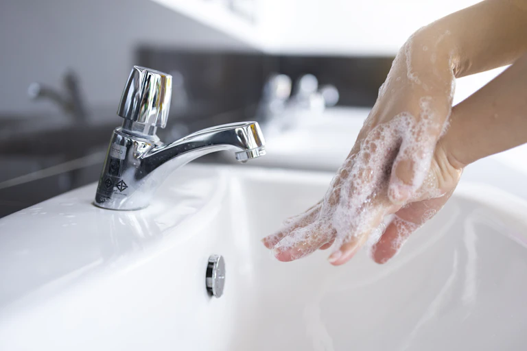 A person washing their hands over a sink.