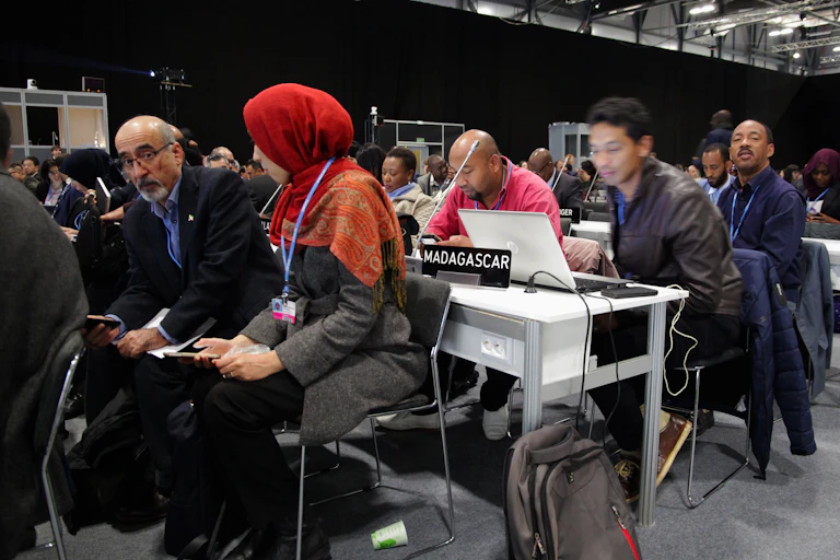 A diverse group of attendees talking or working on computers at the last COP
