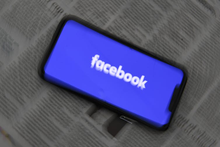 Facebook logo on top of blurry newsprint
