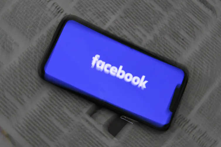 Facebook logo on top of blurry newsprint