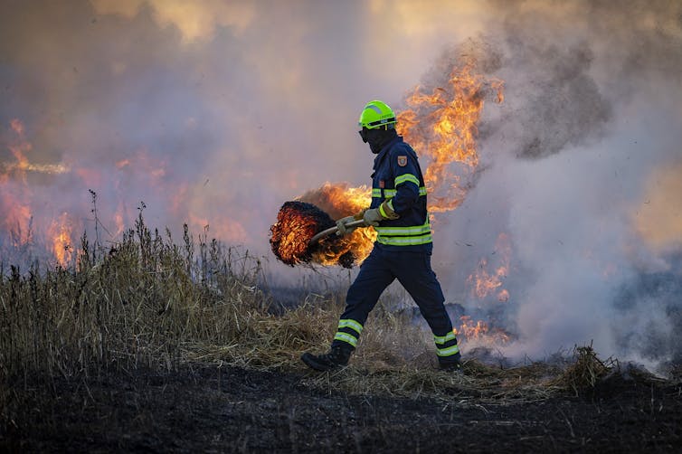 A firefighter walks in a burning field