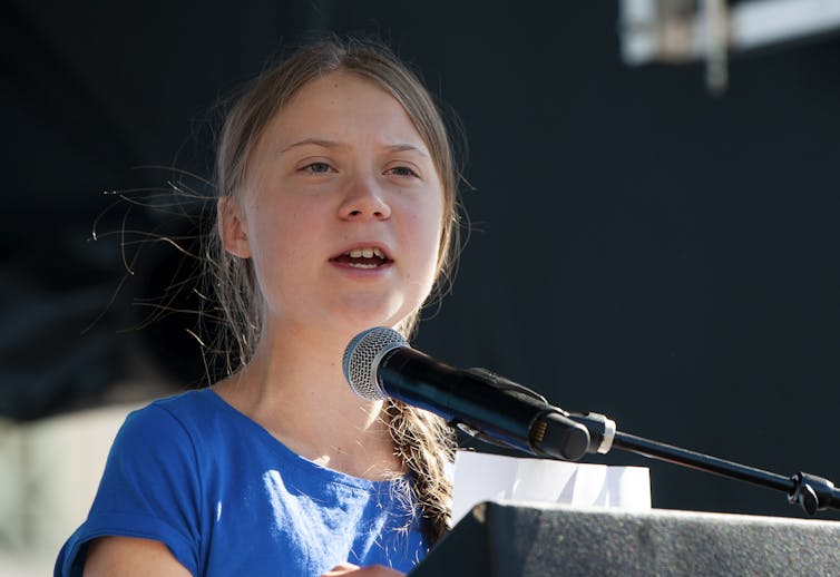 Greta Thunberg talks at a podium on a march