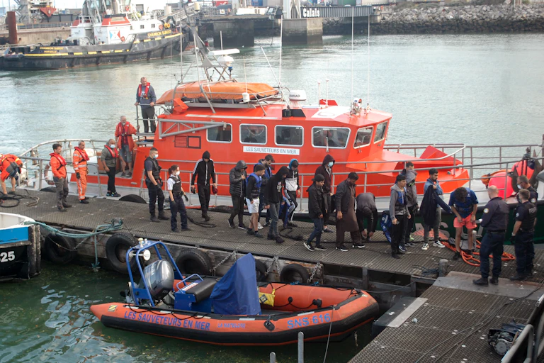 Des migrants sont escortés alors qu'ils débarquent d'un navire de la Société Nationale de Sauvetage en Mer (SNSM) à Calais, le 15 septembre 2021, après avoir été secourus par un navire de la SNSM alors que leur bateau gonflable se remplissait d'eau dans la Manche.